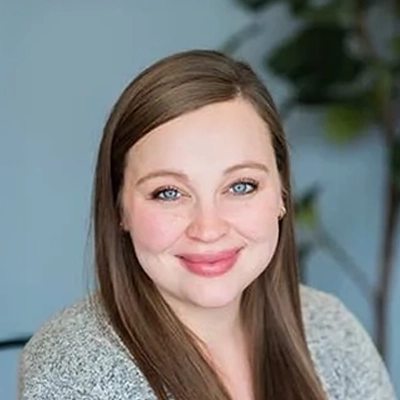 Staci smiling in a grey sweater.