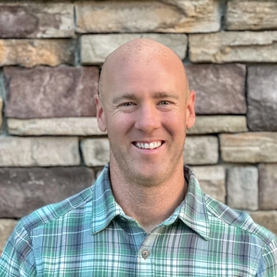 Dr. Jason Barker smiling in a green flannel.