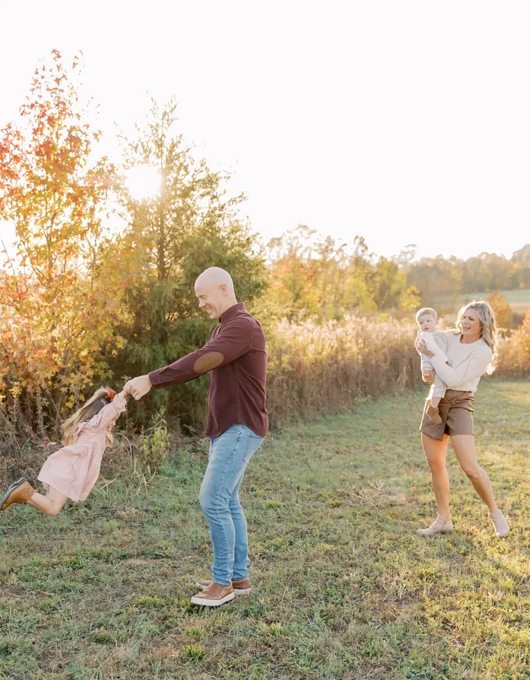 Dr. Jason Barker spinning his daughter in the air while his wife and son watch.