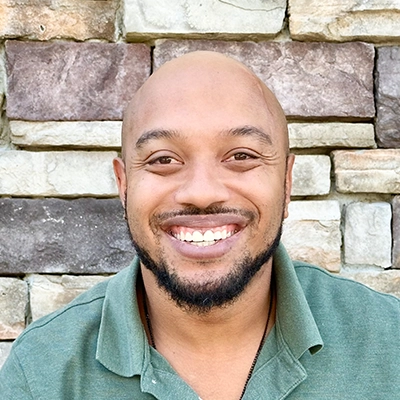 Lonnie smiling in front of a brick wall.