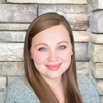 Staci smiling in a grey sweater.