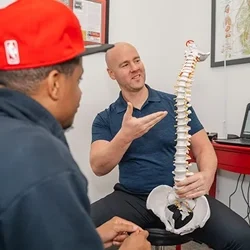 Chiropractor Clemmons NC Jason Barker And Andrew Green Wellness Care A photo grid of 3 photos. One of Dr. Andrew Green going over X-rays. Two of Jason Barker with patients.
